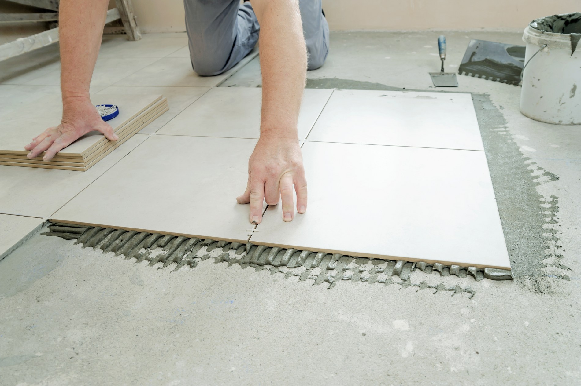 A tiler is putting a spacer between a ceramic tiles.